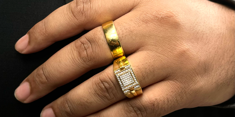 A men wearing two rings, one plain gold and one with diamonds